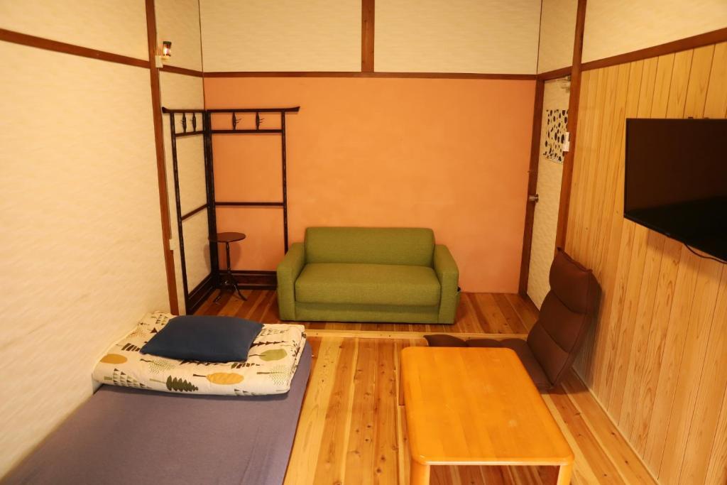 富士宮市にあるGuesthouse TOKIWA - Vacation STAY 01074vの緑の椅子とテーブルが備わる客室です。