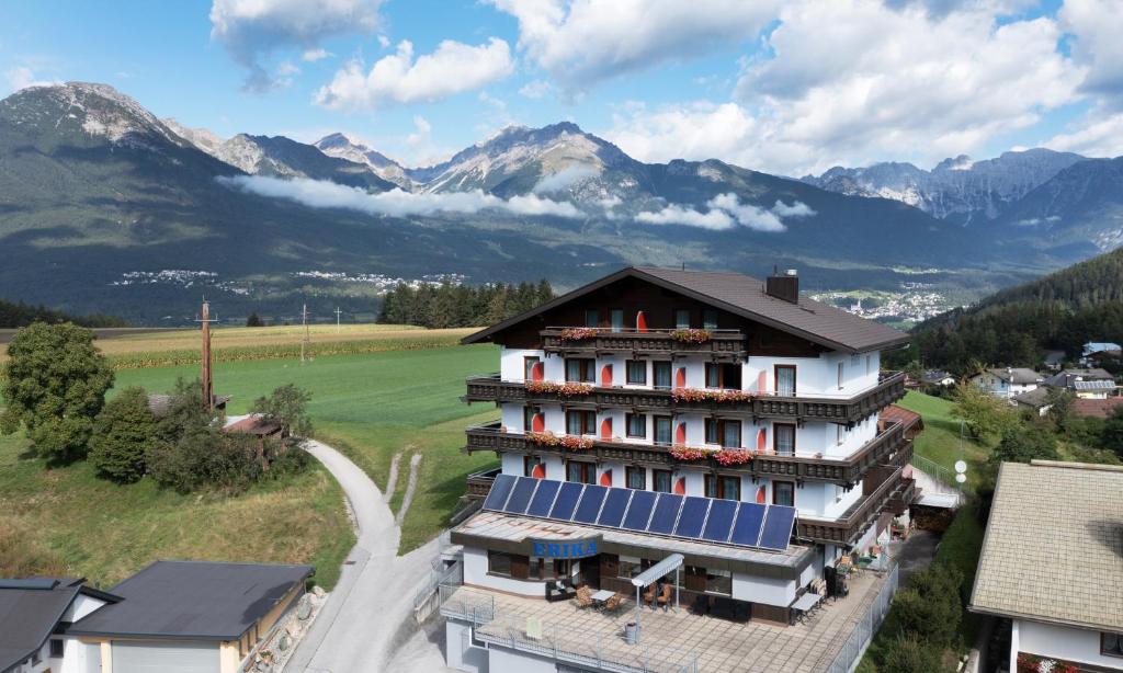 un grande edificio con pannelli solari e montagne di Hotel Erika ad Arzl im Pitztal