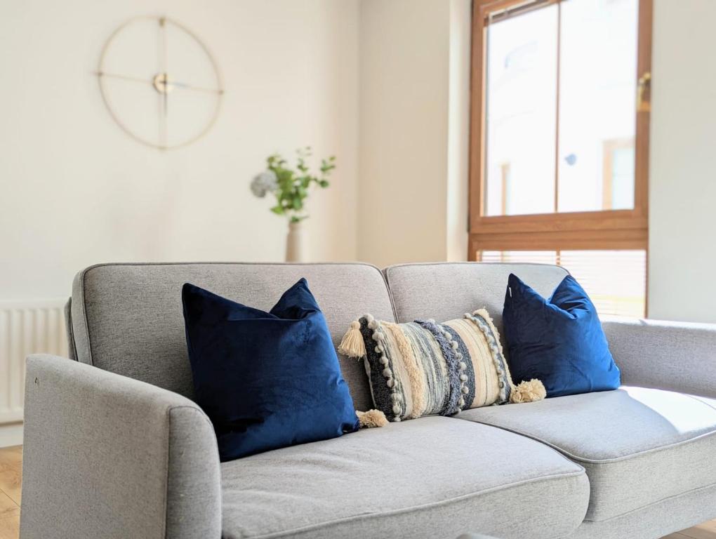a gray couch with blue pillows in a living room at Brooklands Central Apartment in Newcastle
