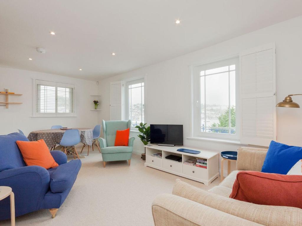 a living room with blue chairs and a tv at College View 2 Lower in Kingswear