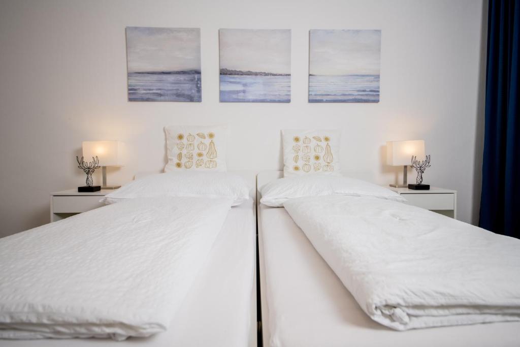 two beds in a white bedroom with pictures on the wall at atrium roselina in Kirchstetten