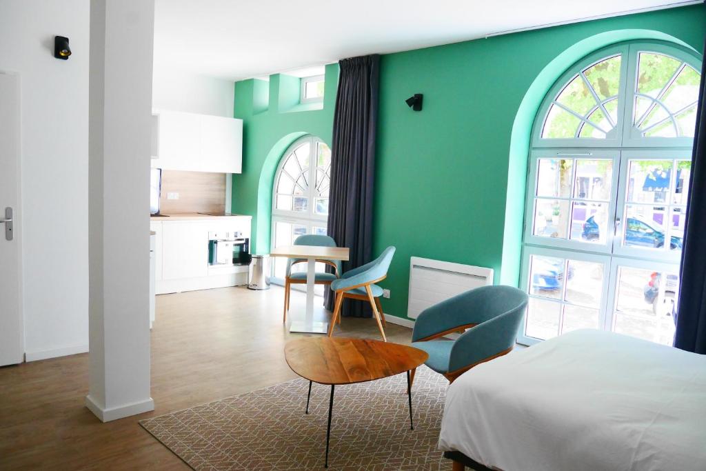a bedroom with green walls and a bed and chairs at Première Pierre in Verdelais