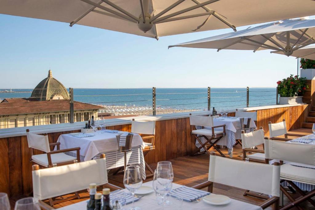 a restaurant with white tables and chairs and the ocean at Grand Hotel Principe Di Piemonte in Viareggio