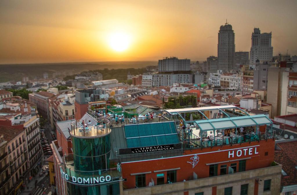 una barca da tour in cima a un edificio con il tramonto sullo sfondo di Hotel Santo Domingo a Madrid