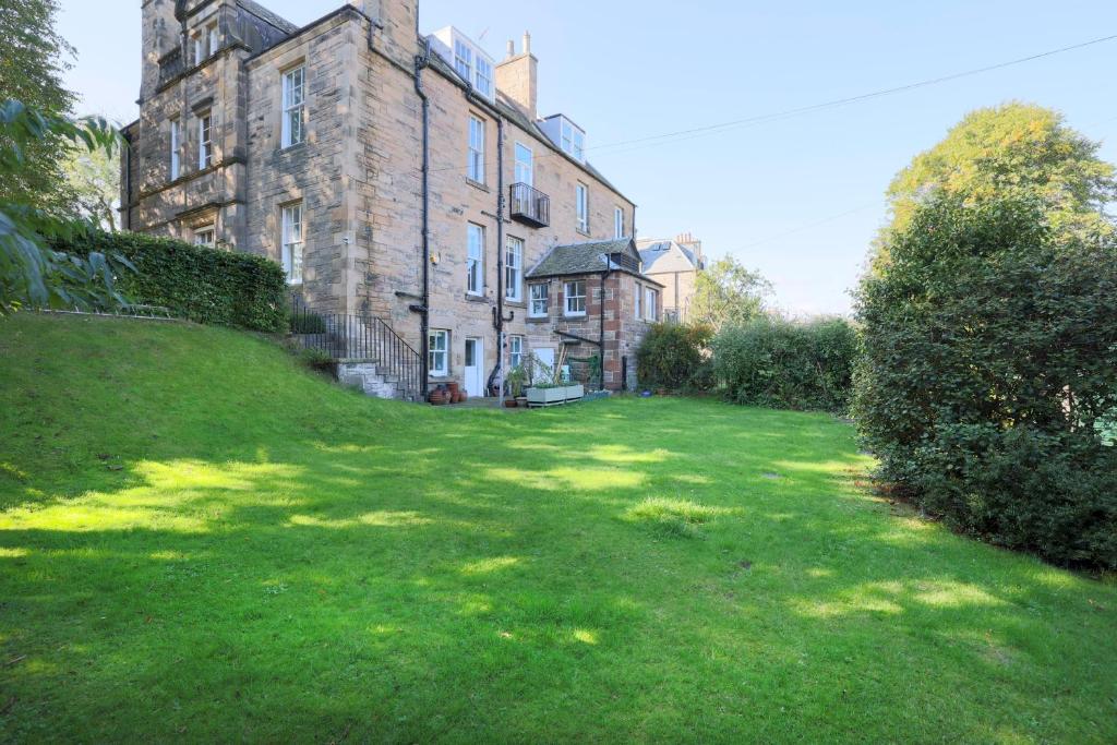 an old building with a grass yard in front of it at JOIVY Lovely 4 bed house, private garden and free parking in Edinburgh