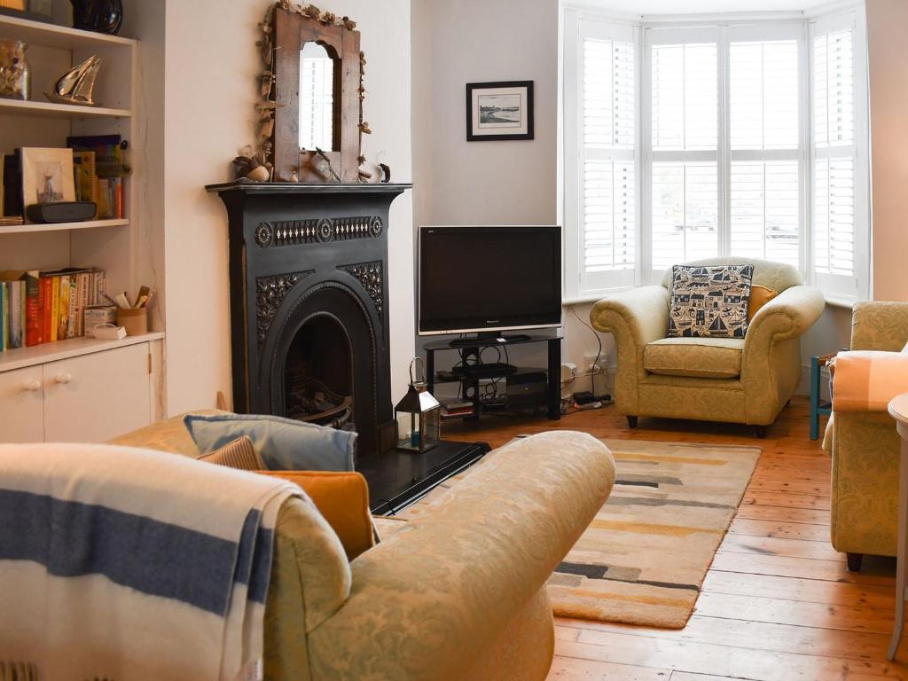 a living room with a fireplace and a television at Blue Cottage in Broadstairs