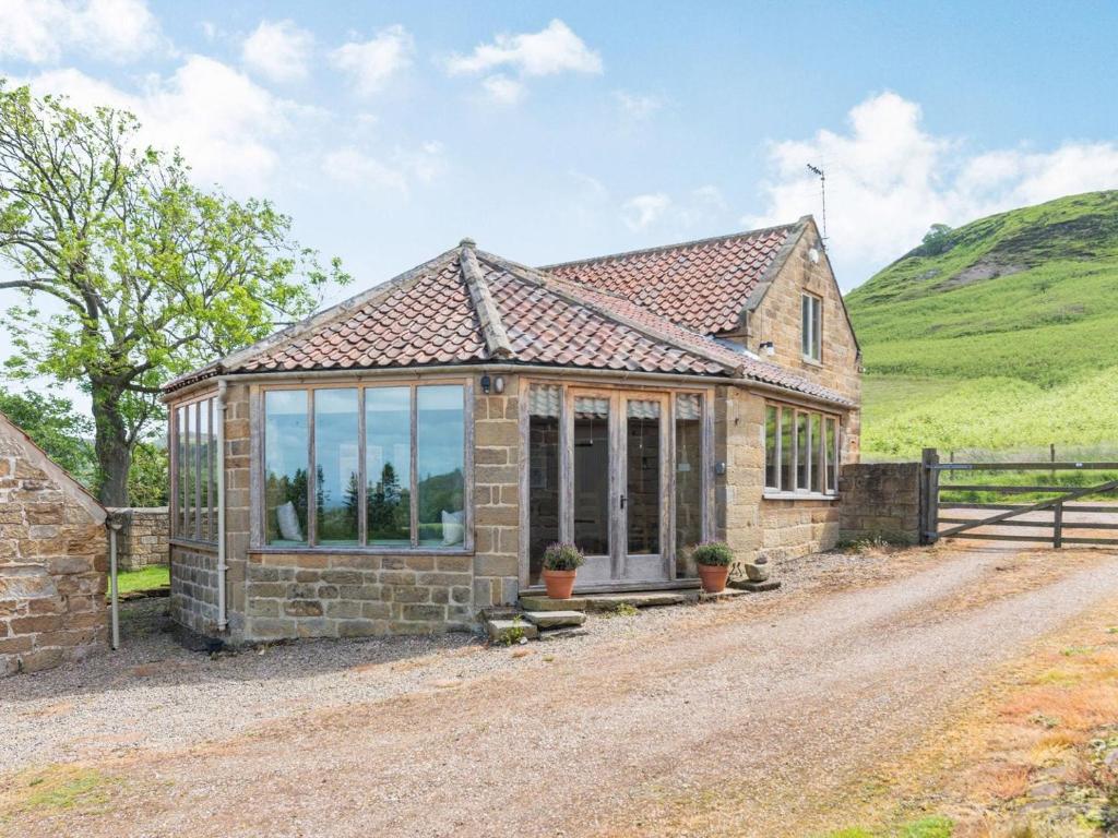 a stone house with large windows on a dirt road at The Wheel House in Potto