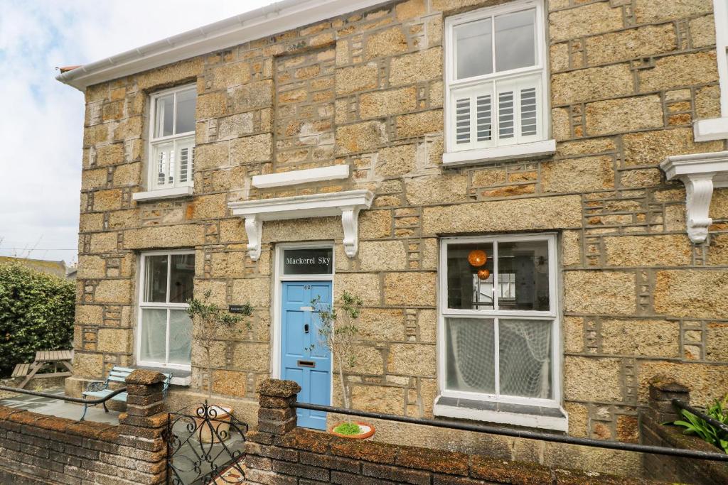 a brick house with a blue door and windows at Mackerel Sky in Penzance