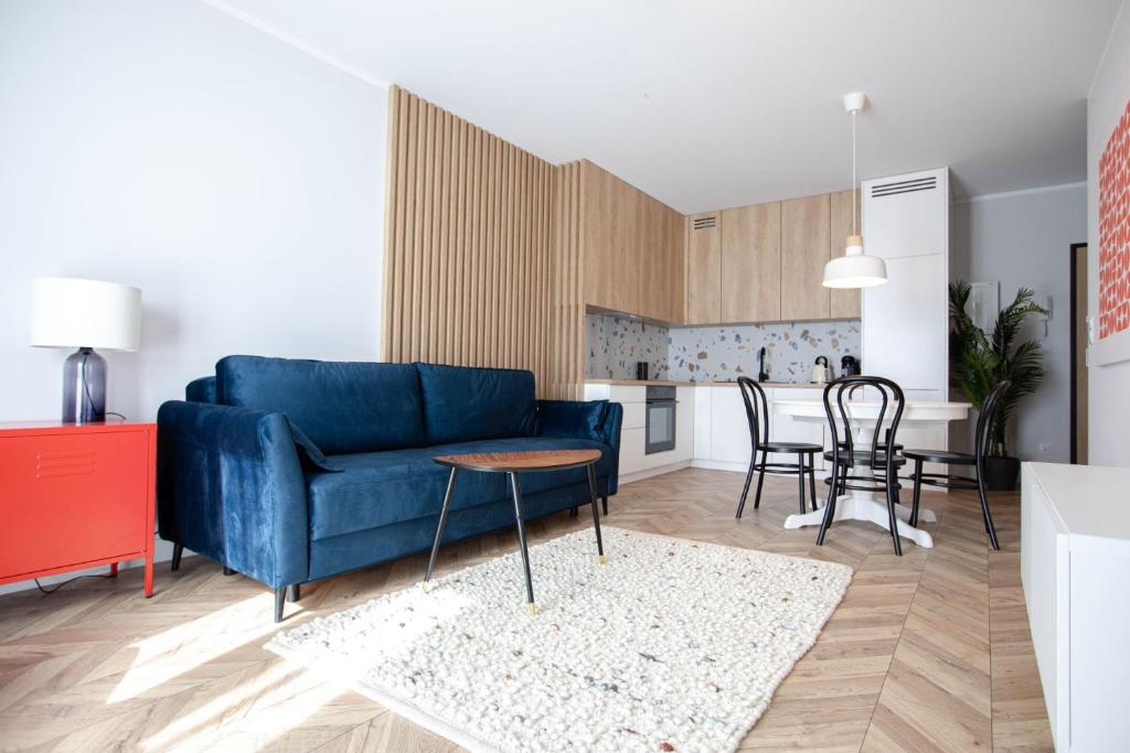 uma sala de estar com um sofá azul e uma cozinha em Rent40 Apartamenty Aura Gdańsk Old Town em Gdansk