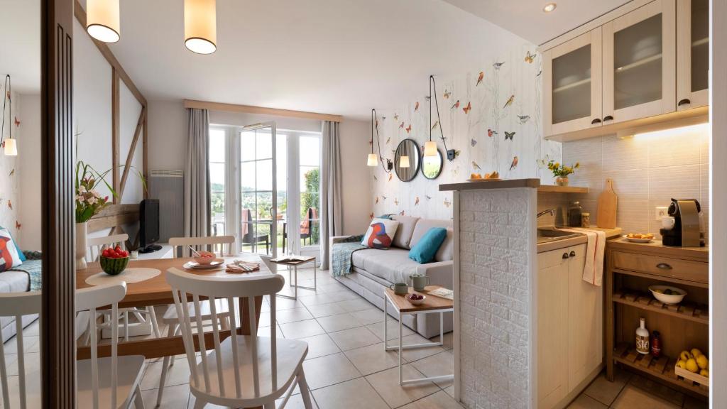 a kitchen and living room with a table and a living room at Pierre & Vacances Premium Residence & Spa Houlgate in Houlgate