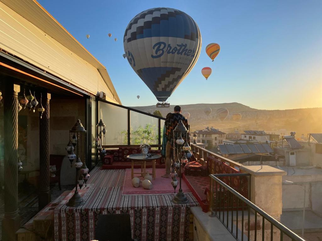 a man standing on a balcony looking at a hot air balloon at Olivia Cave Hotel in Göreme