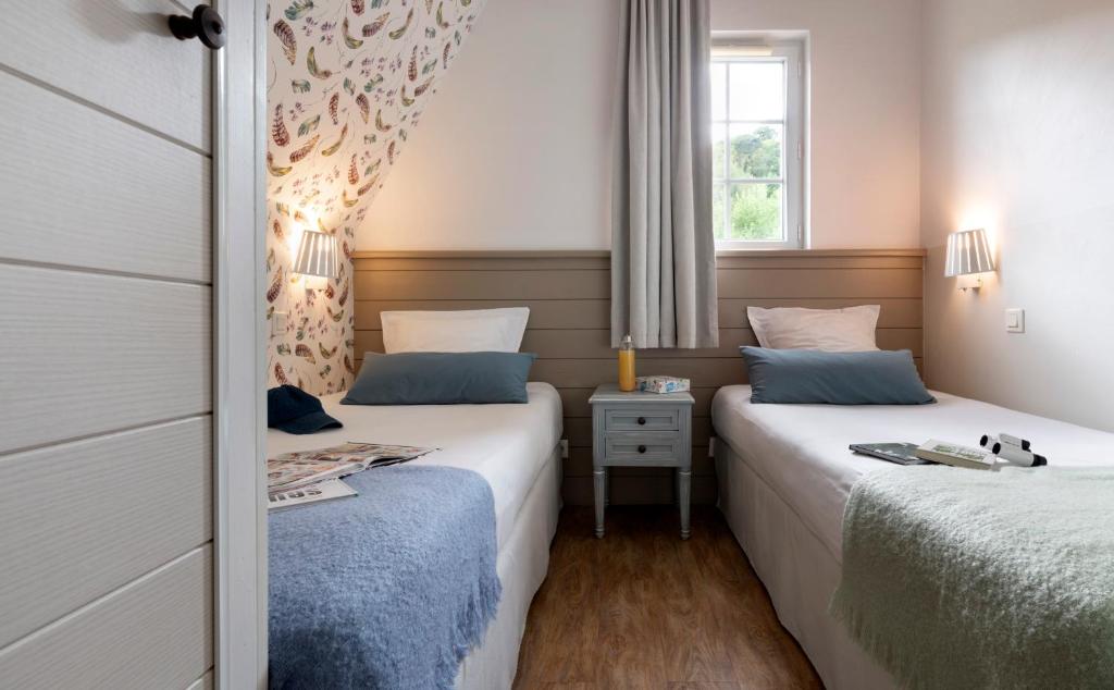 two beds in a small bedroom with a window at Pierre & Vacances Premium Residence & Spa Houlgate in Houlgate