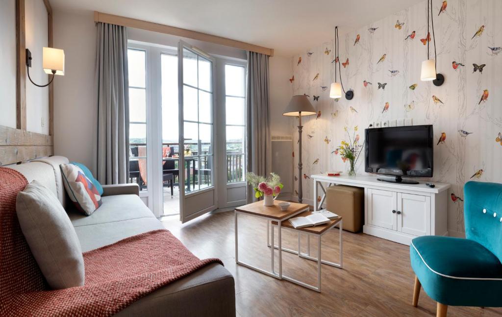 a living room with a couch and a tv at Pierre & Vacances Premium Residence & Spa Houlgate in Houlgate