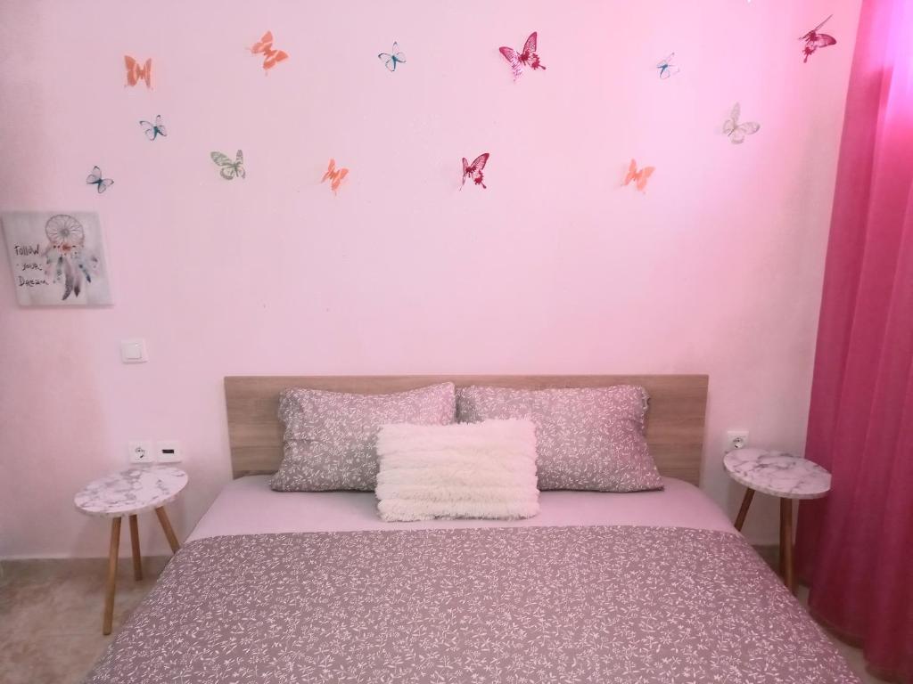 um quarto com uma cama com paredes cor-de-rosa e borboletas na parede em PUZZLE SWEET HOME em Serres