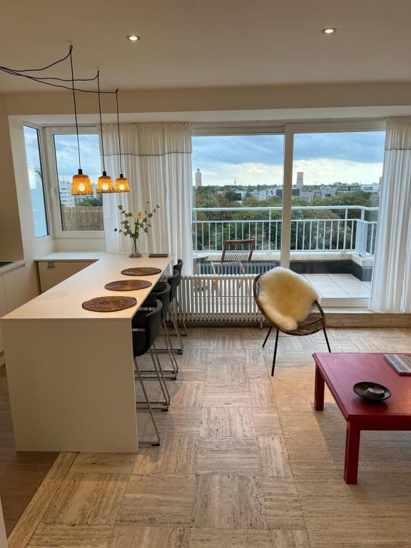 a kitchen with a island with chairs and a large window at Penthouse Mathilde in Ostend