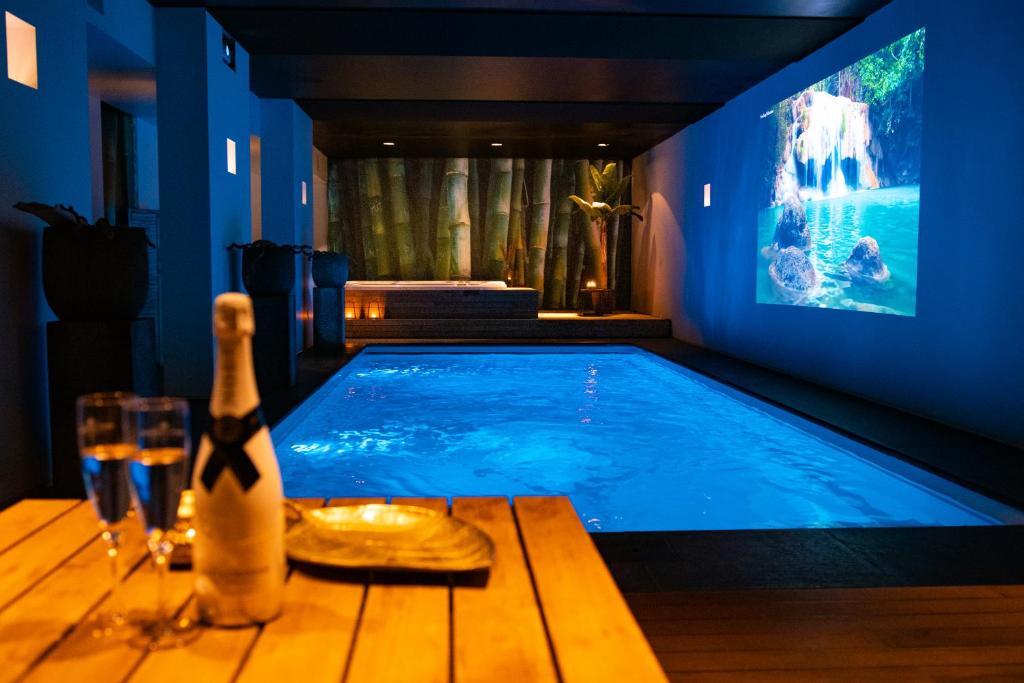 Bed & Wellness Boxtel في بوكستيل: حمام سباحة في غرفة مع زجاجة من النبيذ
