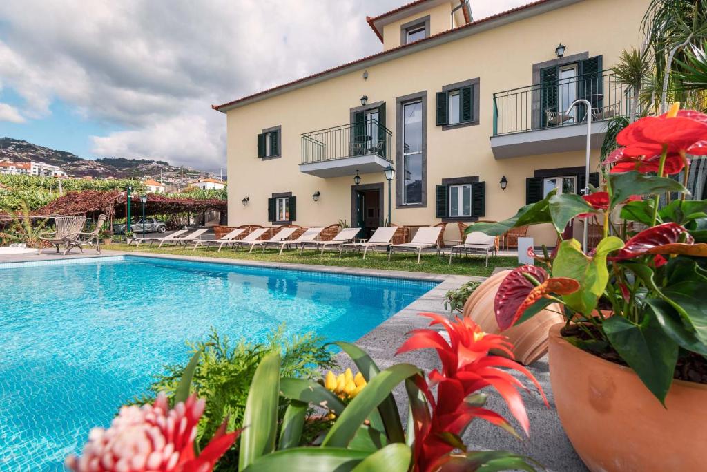 a swimming pool in front of a house with flowers at Quinta da Saraiva in Câmara de Lobos
