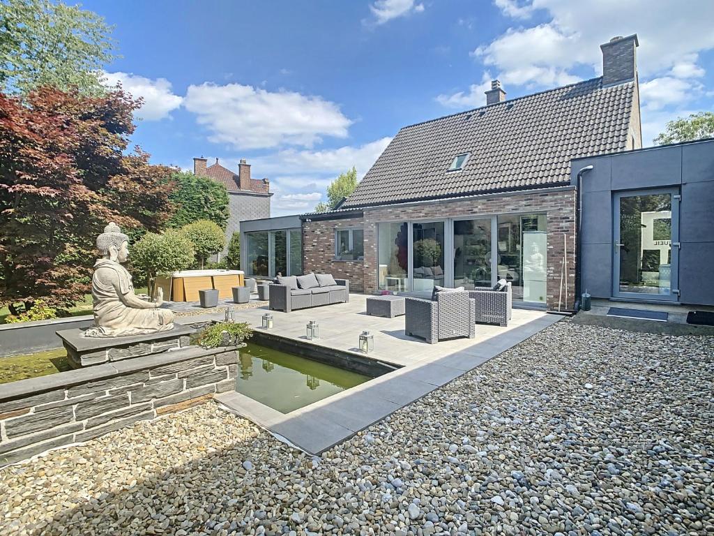 a home with a statue in the yard at Maison 2 ch avec Piscine intérieure et Spa privatif in Floreffe