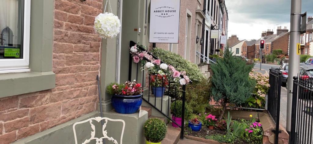 a building with potted plants and a bench on a street at Abbey House B & B in Penrith