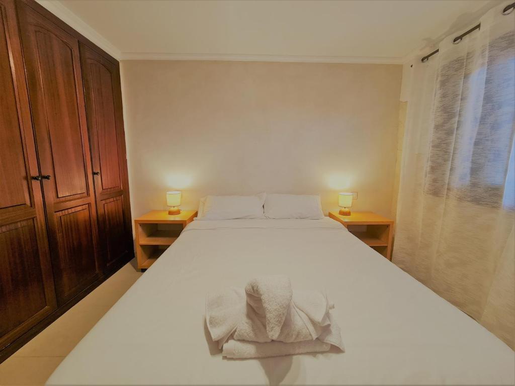 Un dormitorio con una cama blanca con toallas. en El Olivar Aulaga Beach, en Puerto del Rosario