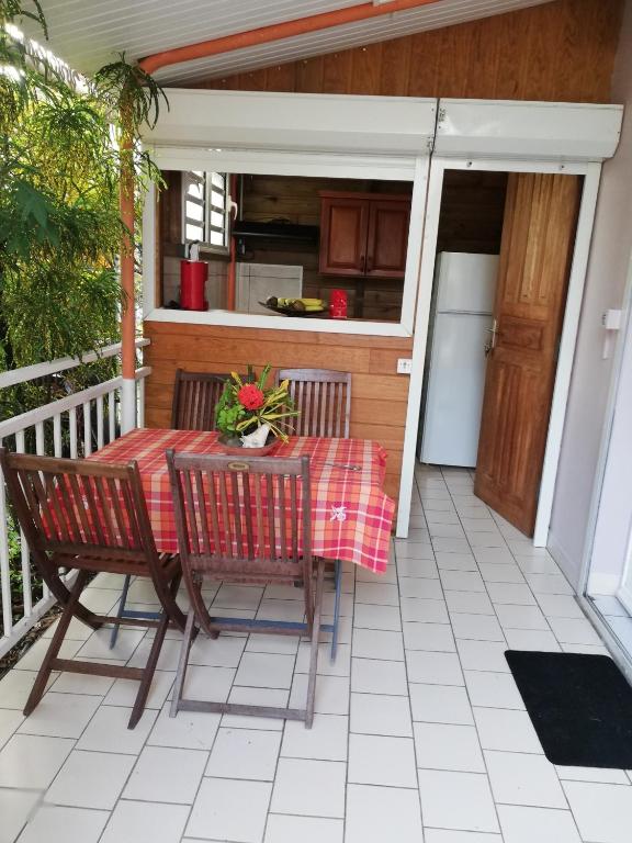 a table and chairs on the porch of a house at Studio Griyav- dans villa les Polycias in Sainte-Luce