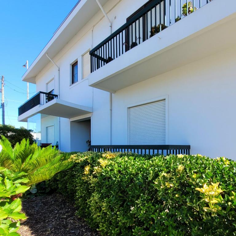 a white house with a balcony and some bushes at Aguda Golf Vita Apartamento 2 Quartos in Arcozelo