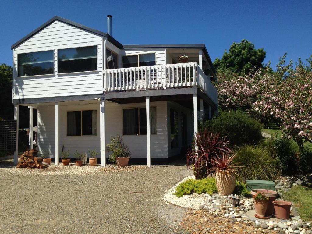 Casa blanca con balcón y algunas plantas en Yarra Glen Bed & Breakfast, en Yarra Glen