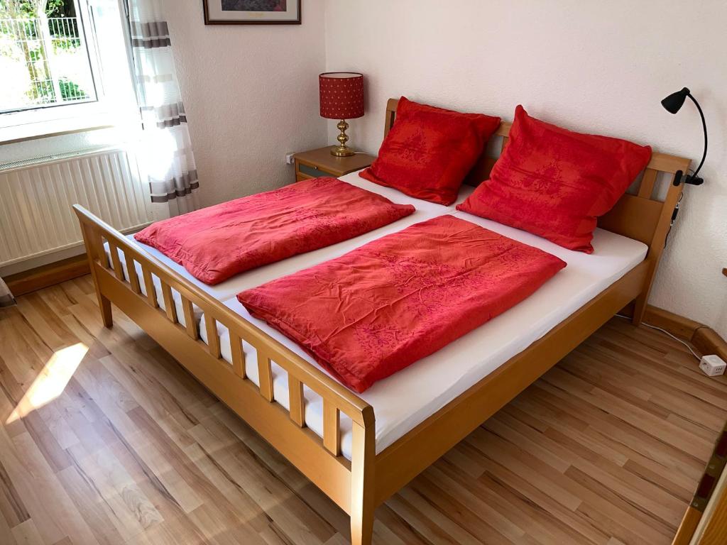 a bed with red pillows on it in a room at FeWo HoLiDay ApartMENT Allgäu in Ottobeuren