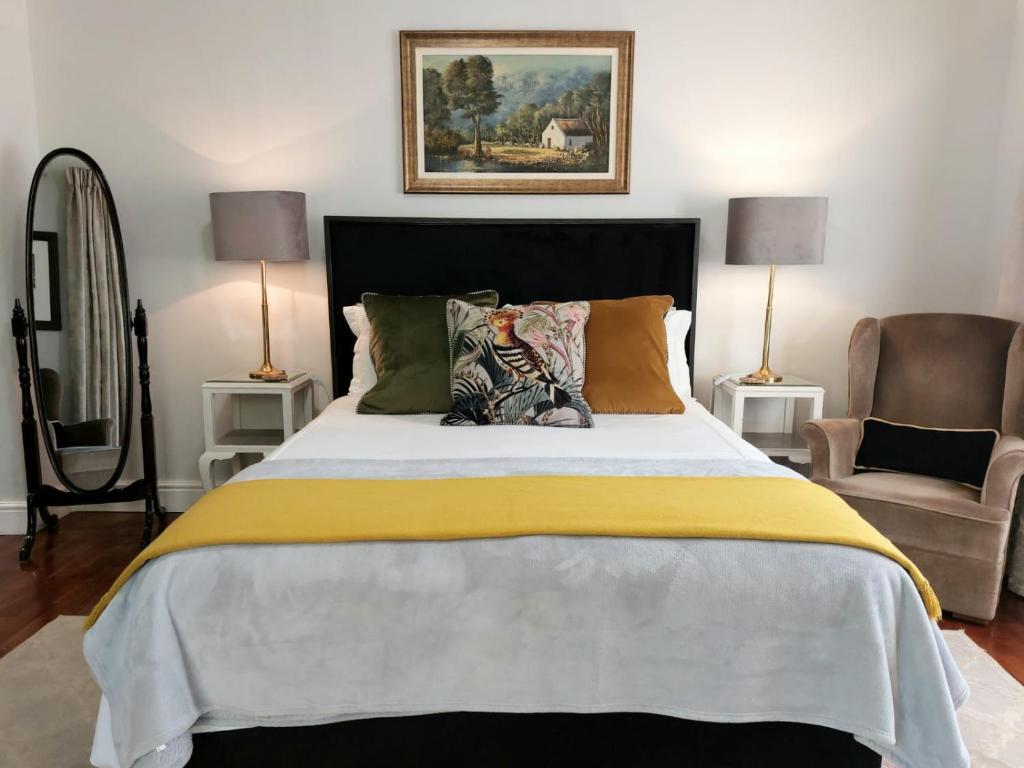 a bedroom with a bed with a yellow blanket and a chair at Daisy Place in Franschhoek