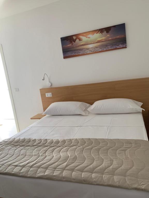 a bedroom with a white bed with a picture on the wall at Miriasol Bed and Breakfast in Capo Vaticano