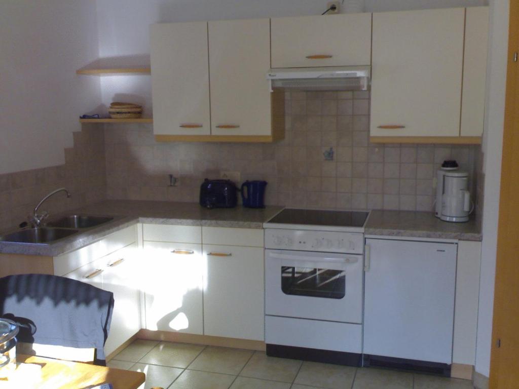 a kitchen with white cabinets and a white stove top oven at Haus Waldfriede in Pertisau