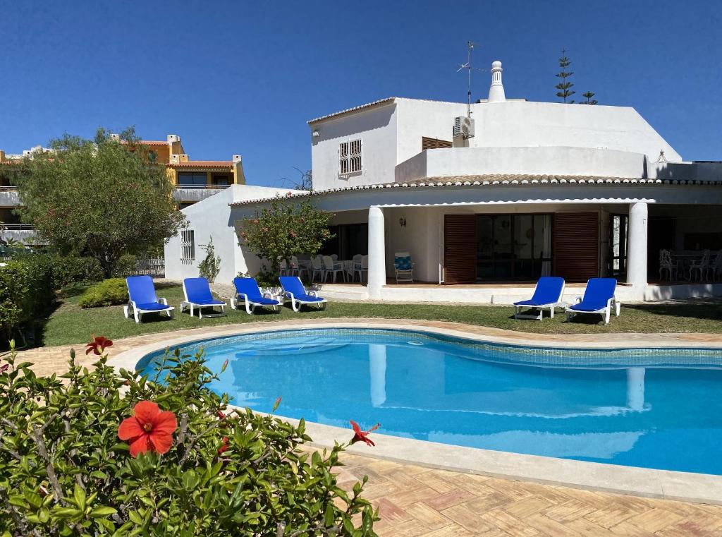 une piscine avec des chaises bleues et une maison dans l'établissement Vivenda Júlia e Tavares, à Vilamoura