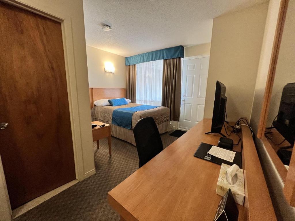 a hotel room with a bed and a desk with a computer at Motel Du Chevalier in Gatineau