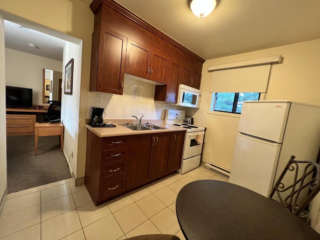 a kitchen with wooden cabinets and a white refrigerator at Motel Du Chevalier in Gatineau