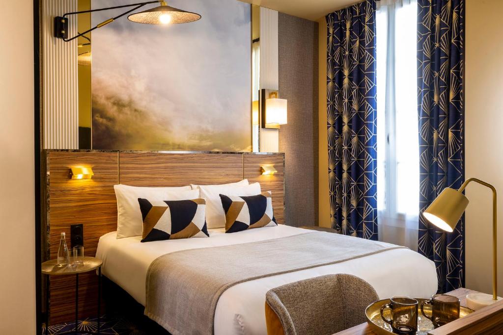 een hotelkamer met een groot bed en een stoel bij Hotel Le Rocroy in Parijs