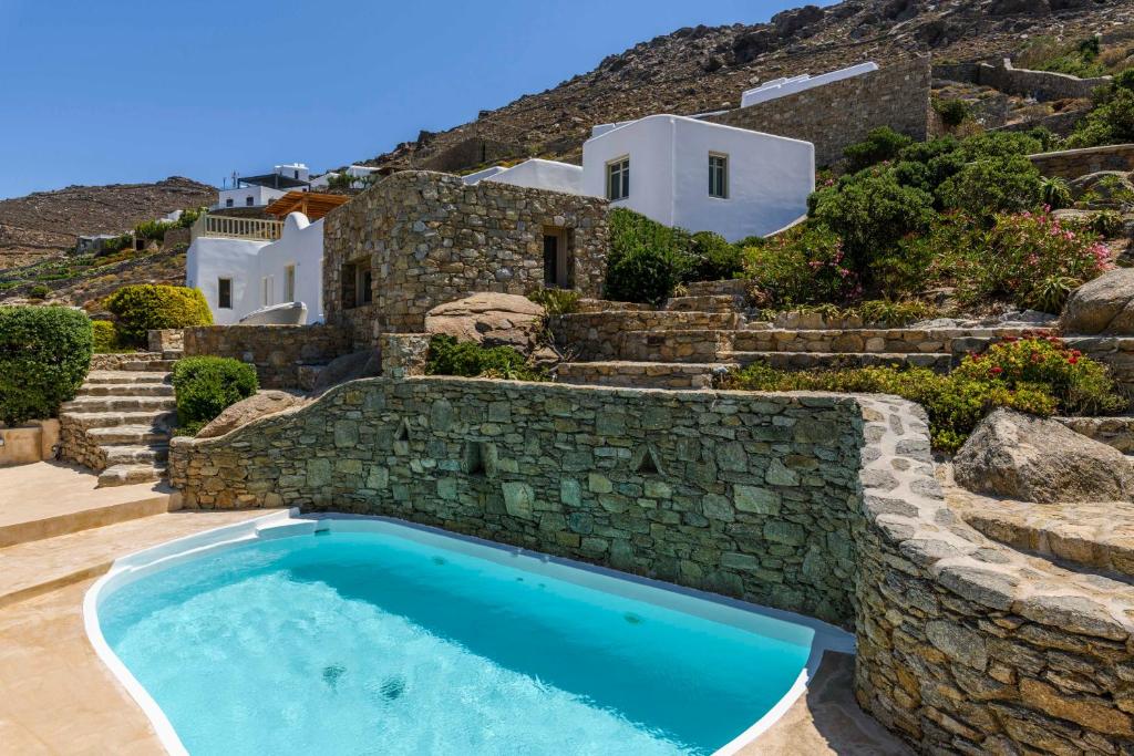 a swimming pool in front of a house with a stone wall at Villa Isabella Family villa close to the beach in Mýkonos City