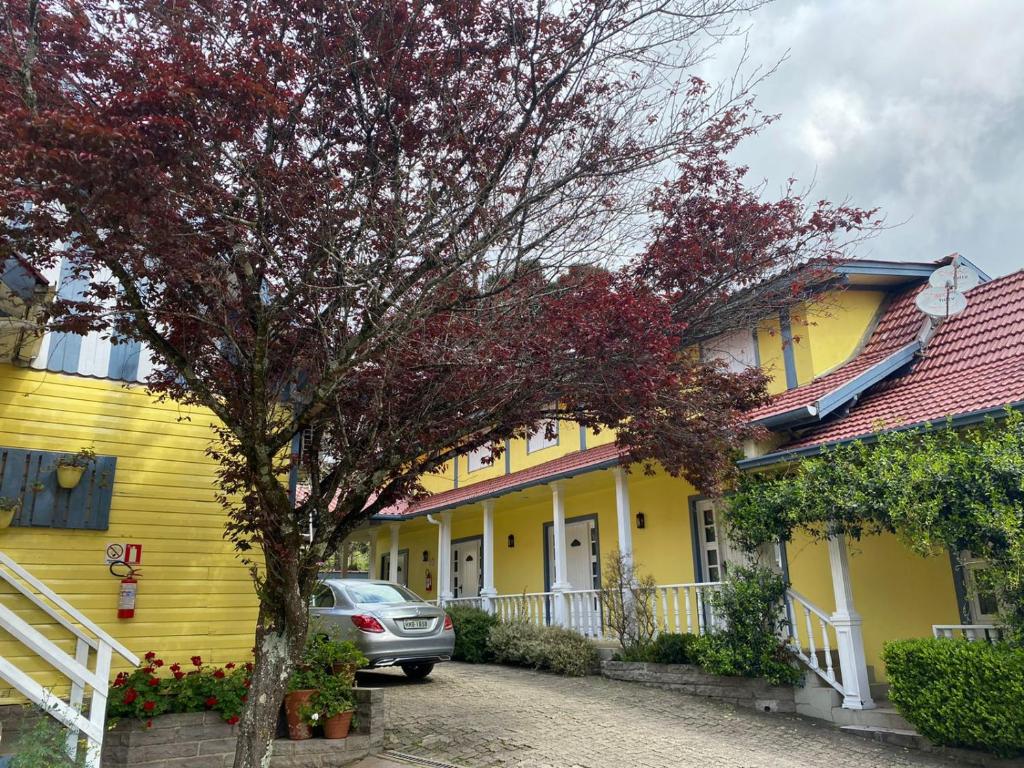 a yellow house with a car parked in front of it at Apartamentos Sulla Collina Centro de Gramado localizado próximo da rua Coberta in Gramado