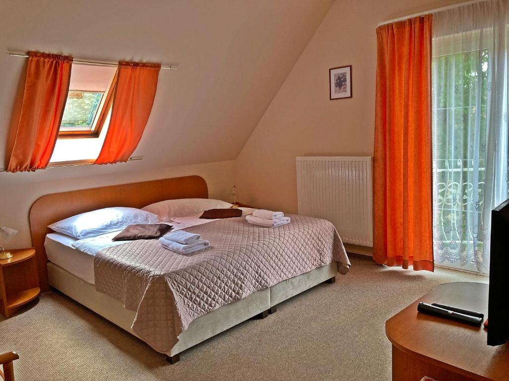 Schlafzimmer mit einem Bett mit orangefarbenen Vorhängen in der Unterkunft Hotel Penta Lux in Tata