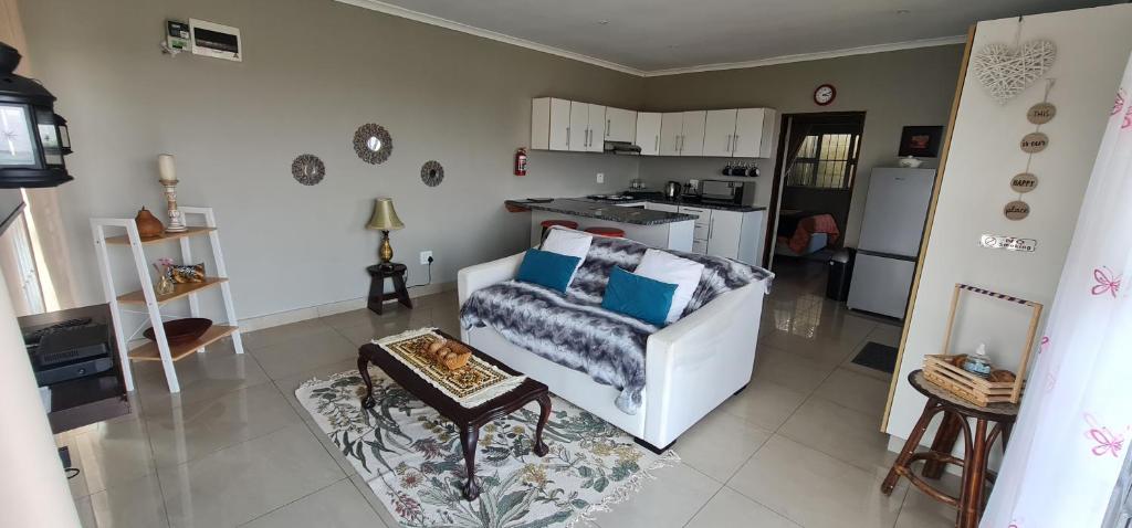 a living room with a white couch and a kitchen at Cosy Cottage in Port Shepstone