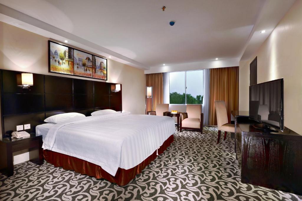 a hotel room with a bed and a flat screen tv at ASTON Karimun City Hotel in Tanjung Balai Karimun
