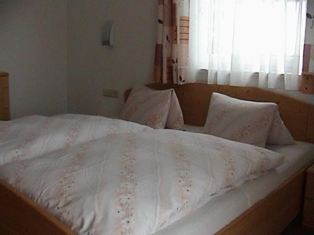 a bed with a white comforter and pillows at Haus Waldfriede in Pertisau
