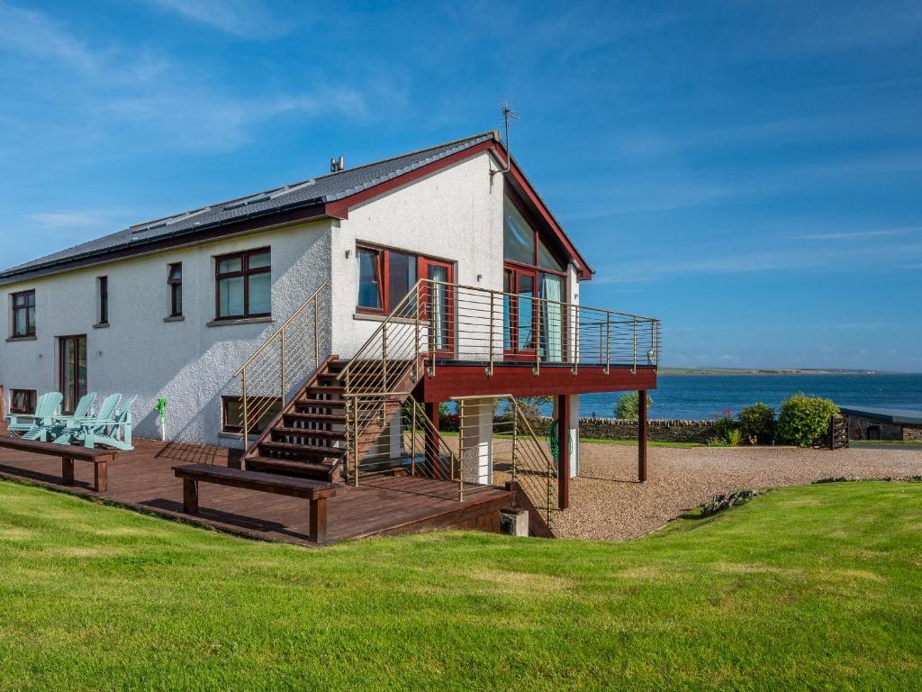 a house on the beach with a deck and stairs at The Steading in Stromness