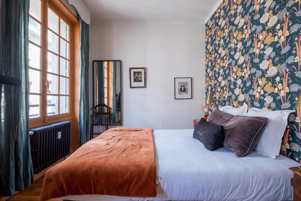 a bedroom with a large bed with a floral headboard at Honorê - Suite Jacobins in Lyon