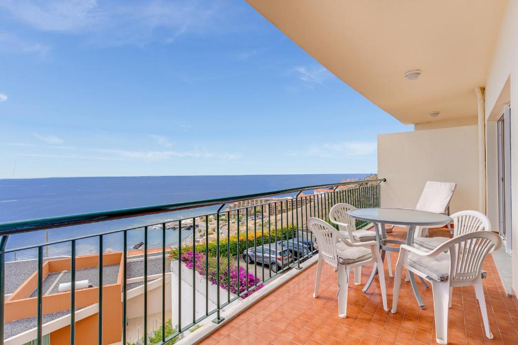 a balcony with a table and chairs and the ocean at Reis Magos Apartment by HR Madeira in Caniço