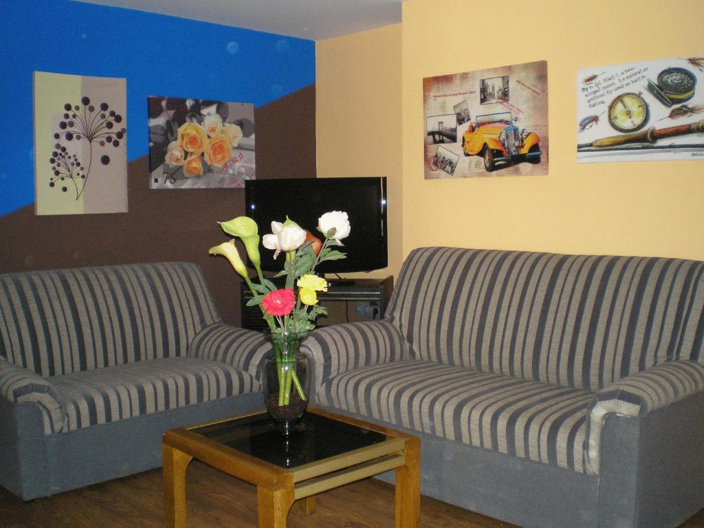 una sala de estar con 2 sofás y un jarrón de flores en Apartamentos Augusta Centro, en Zaragoza