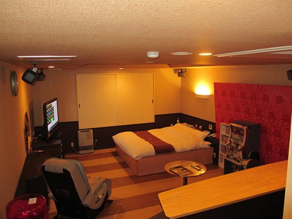 een slaapkamer met een bed, een bureau en een stoel bij ホテル アルファ in Iizaka