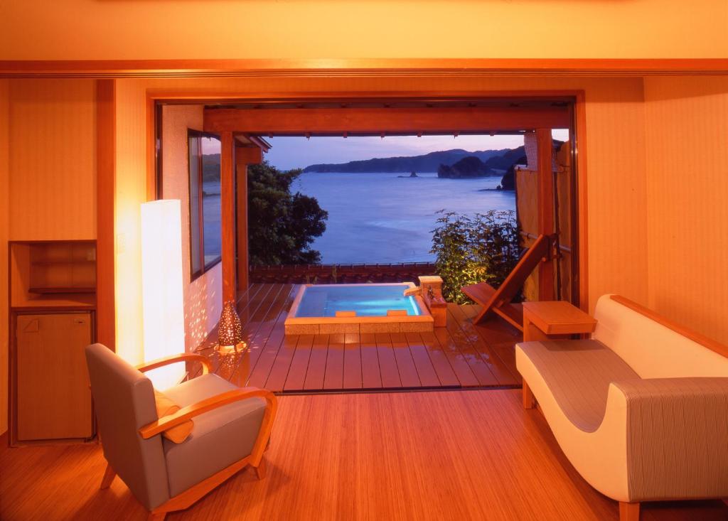 a living room with a view of a swimming pool at Shimoda Yamatokan in Shimoda