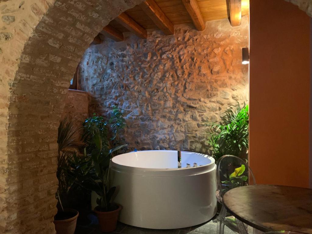 uma banheira num quarto com uma parede de pedra em WUNDERGARTEN Rural Spa House em Gratteri