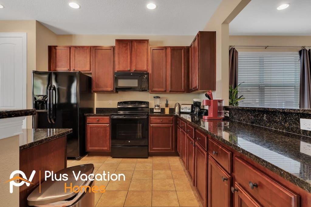 a large kitchen with wooden cabinets and black appliances at 371-Luxury Villa with POOL in Orlando