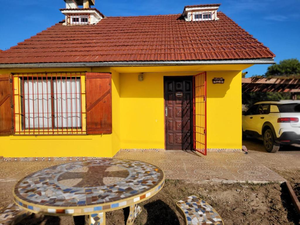 una casa amarilla con una mesa delante en Casa Amarrilla en San Clemente del Tuyú